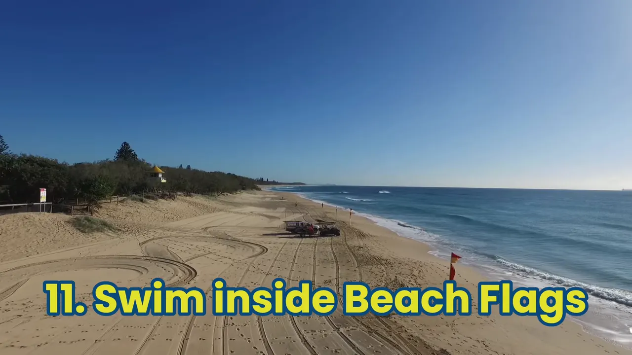 aerial view of a patrolled sandy beach showing flagged swimming area and on-screen text '11. Swim inside Beach Flags'